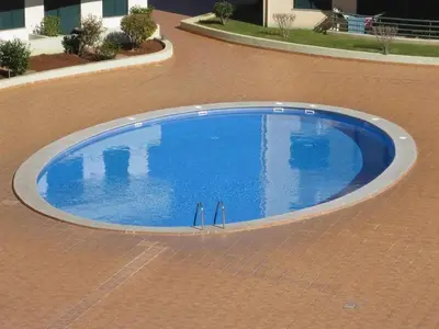 a large blue swimming pool on a brick floor at Pia's Place - Apt with sea view in Caniço