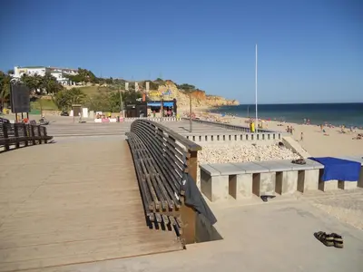 a bench on a boardwalk next to a beach at Vivenda Solmar in Lagos