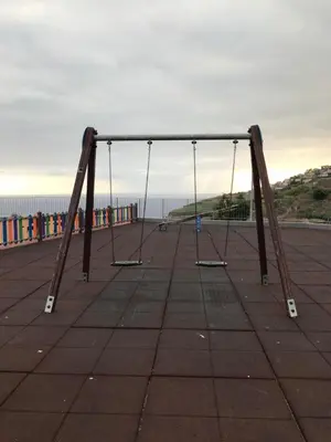 an empty swing set on a pier near the ocean at Lou-Jos in Funchal