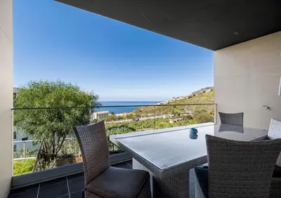 a balcony with a table and chairs and the ocean at Madeira Mar - 