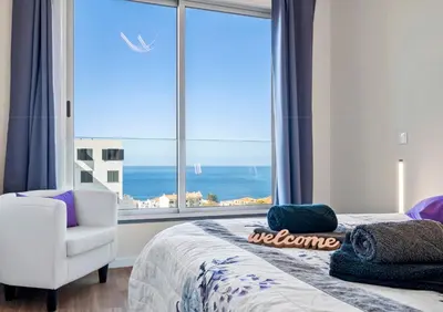 a bedroom with a bed and a chair and a large window at Madeira Mar - 