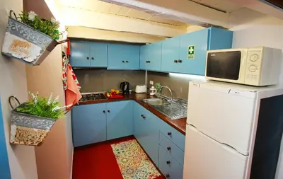 a small kitchen with blue cabinets and a white refrigerator at Casa Benedita in Ponta do Pargo