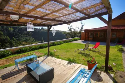 a patio with chairs and a table and a pergola at Casa Benedita in Ponta do Pargo