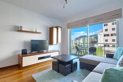 a living room with a couch and a tv at Blue Sky Apartment with pool by Holiday Rental Madeira in Funchal