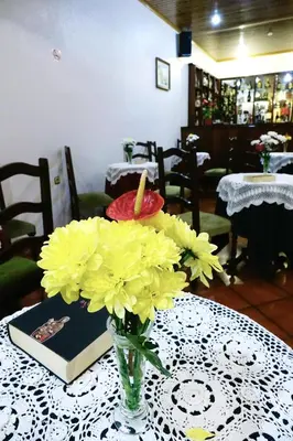 a vase of yellow flowers on a table with a book at Hotel GORDON in Funchal