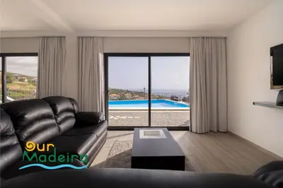 a living room with a leather couch and a view of a pool at OurMadeira - Casa da Rosalina in Calheta