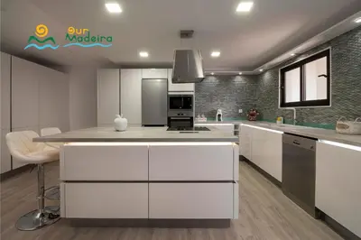 a kitchen with white cabinets and stainless steel appliances at OurMadeira - Casa da Rosalina in Calheta