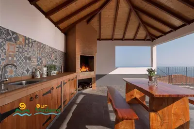 a kitchen with a fireplace and a table and a sink at OurMadeira - Casa da Rosalina in Calheta