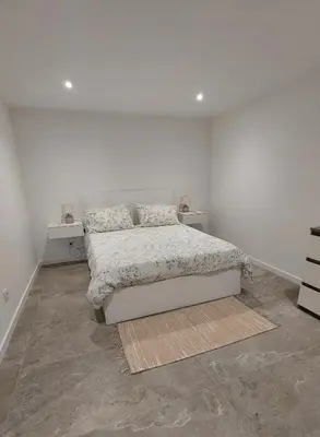 a white bedroom with a bed and two night stands at Estúdio Laura in Câmara de Lobos