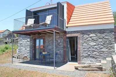 a house with a balcony with two chairs and a table at OurMadeira - Quinta Inácia in Calheta