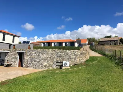 a stone wall with a bench next to a building at OurMadeira - Quinta Inácia in Calheta