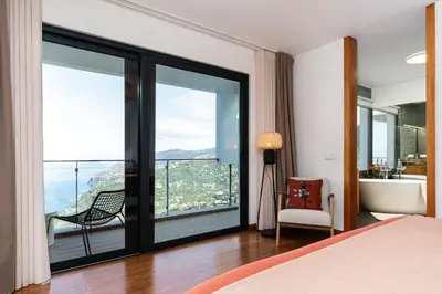 a bedroom with a bed and a balcony with a view at Valley View-Villa with heated pool and sauna in Arco da Calheta