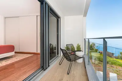 a room with a balcony with a table and a chair at Valley View-Villa with heated pool and sauna in Arco da Calheta