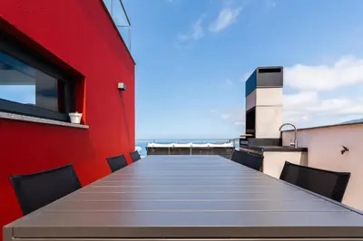 a long table with chairs and a red wall at Valley View-Villa with heated pool and sauna in Arco da Calheta