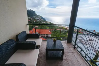 a balcony with a couch and a table and the ocean at Calheta Holiday Houses in Arco da Calheta