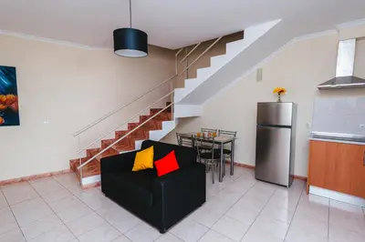 a living room with a black couch and a table at Calheta Holiday Houses in Arco da Calheta