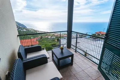 a balcony with two chairs and a table and the ocean at Calheta Holiday Houses in Arco da Calheta