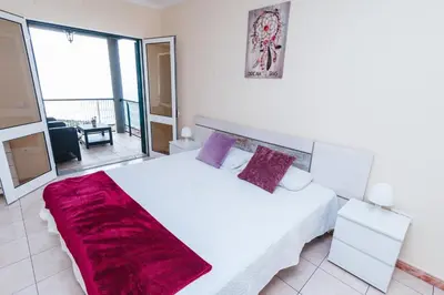 a bedroom with a large white bed with purple pillows at Calheta Holiday Houses in Arco da Calheta
