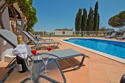 a pool with chairs and a table with wine glasses at Casa da Ladeira Branca in Lagos