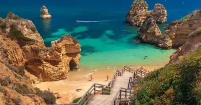 a staircase leading to a beach with rocks and the ocean at Magnoliamar 409 in Lagos