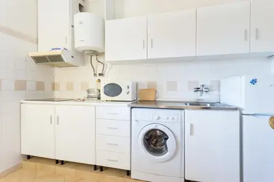 a white kitchen with a washing machine and a sink at Magnoliamar 409 in Lagos