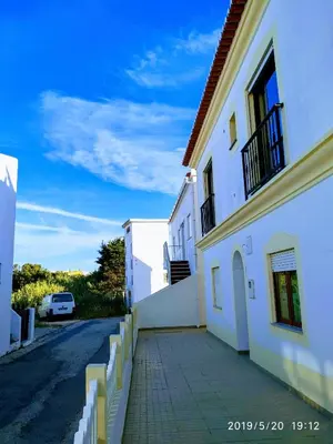 a white building with a sidewalk next to a street at Residencia Quinta do Poço Guesthouse in Sagres
