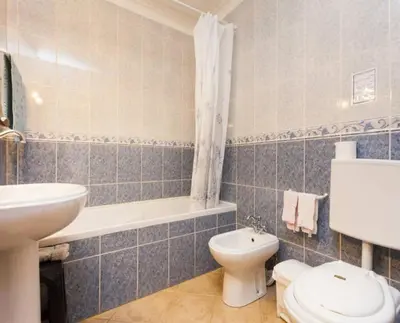 a bathroom with a toilet and a tub and a sink at Residencia Quinta do Poço Guesthouse in Sagres