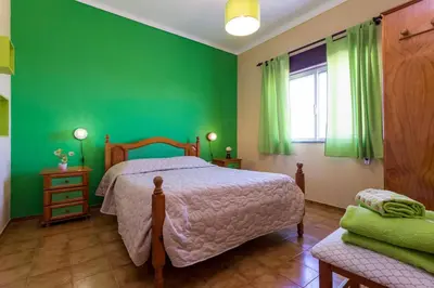 a green bedroom with a bed and a window at Residencia Quinta do Poço Guesthouse in Sagres
