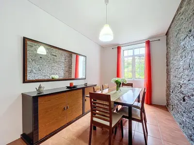 a dining room with a table and a stone wall at Quinta do Serrado II in Ribeira da Janela