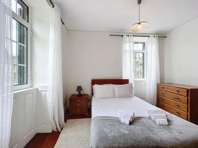 a bedroom with a bed and two windows at Quinta do Serrado II in Ribeira da Janela