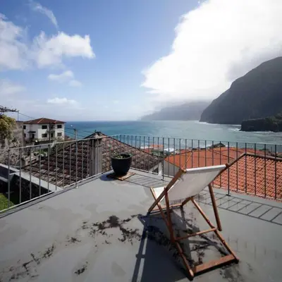 a white chair sitting on top of a balcony overlooking the ocean at Casa do João da Eira in Seixal