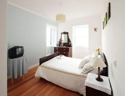 a white bedroom with a bed and a television at Casa do João da Eira in Seixal