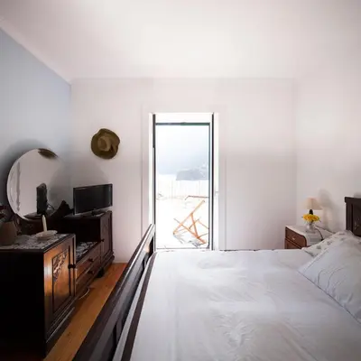 a white bedroom with a bed and a window at Casa do João da Eira in Seixal