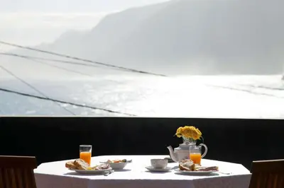 a table with plates of food and a vase of flowers at Casa do João da Eira in Seixal