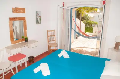 a bedroom with a blue bed and a balcony at Jho'La Surf Camp in Luz