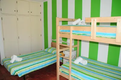 two bunk beds in a room with green and white stripes at Jho'La Surf Camp in Luz