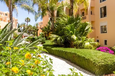 a garden in front of a building with palm trees and flowers at Apartamento Boa Estrela in Luz