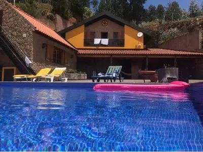 a swimming pool with two chairs and a house at Villa Safari Charm in Ribeira Brava