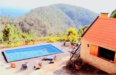a house with a swimming pool in front of a mountain at Villa Safari Charm in Ribeira Brava