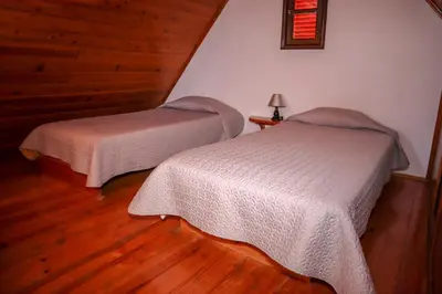two beds in a room with wooden floors at Casas Tipicas Candelaria Tabua in Ponta do Sol