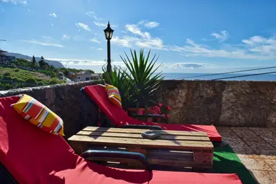 a bench and a table on a patio with a view at Vista Mar, a Home in Madeira in Ponta do Sol
