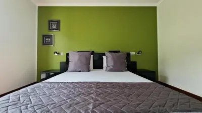 a bedroom with a large bed with green walls at Capela's House by LovelyStay in Ribeira Brava