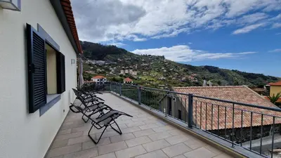a balcony with two chairs and a view of a city at Capela's House by LovelyStay in Ribeira Brava