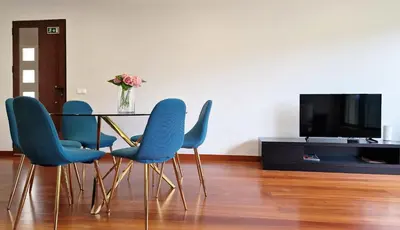 a table with blue chairs and a vase of flowers at Capela's House by LovelyStay in Ribeira Brava