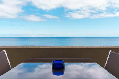 a blue cup sitting on a table in front of the ocean at Sunny Getaway in Funchal in Funchal
