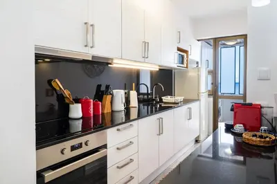a kitchen with white cabinets and a black counter top at Sunny Getaway in Funchal in Funchal