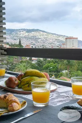 a table with a plate of fruit and orange juice at Condo Magnolia in Funchal
