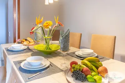 a table with plates of fruit and flowers on it at Condo Magnolia in Funchal