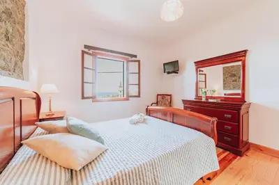 a bedroom with a bed and a dresser and a mirror at Villa Matta by Amazing Madeira in Santana