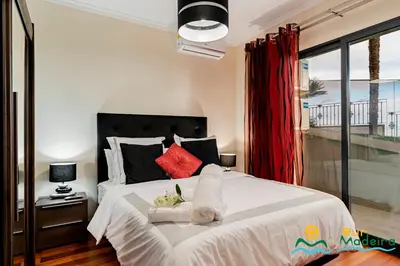 a bedroom with a large white bed with red pillows at OurMadeira - BelAir in Funchal